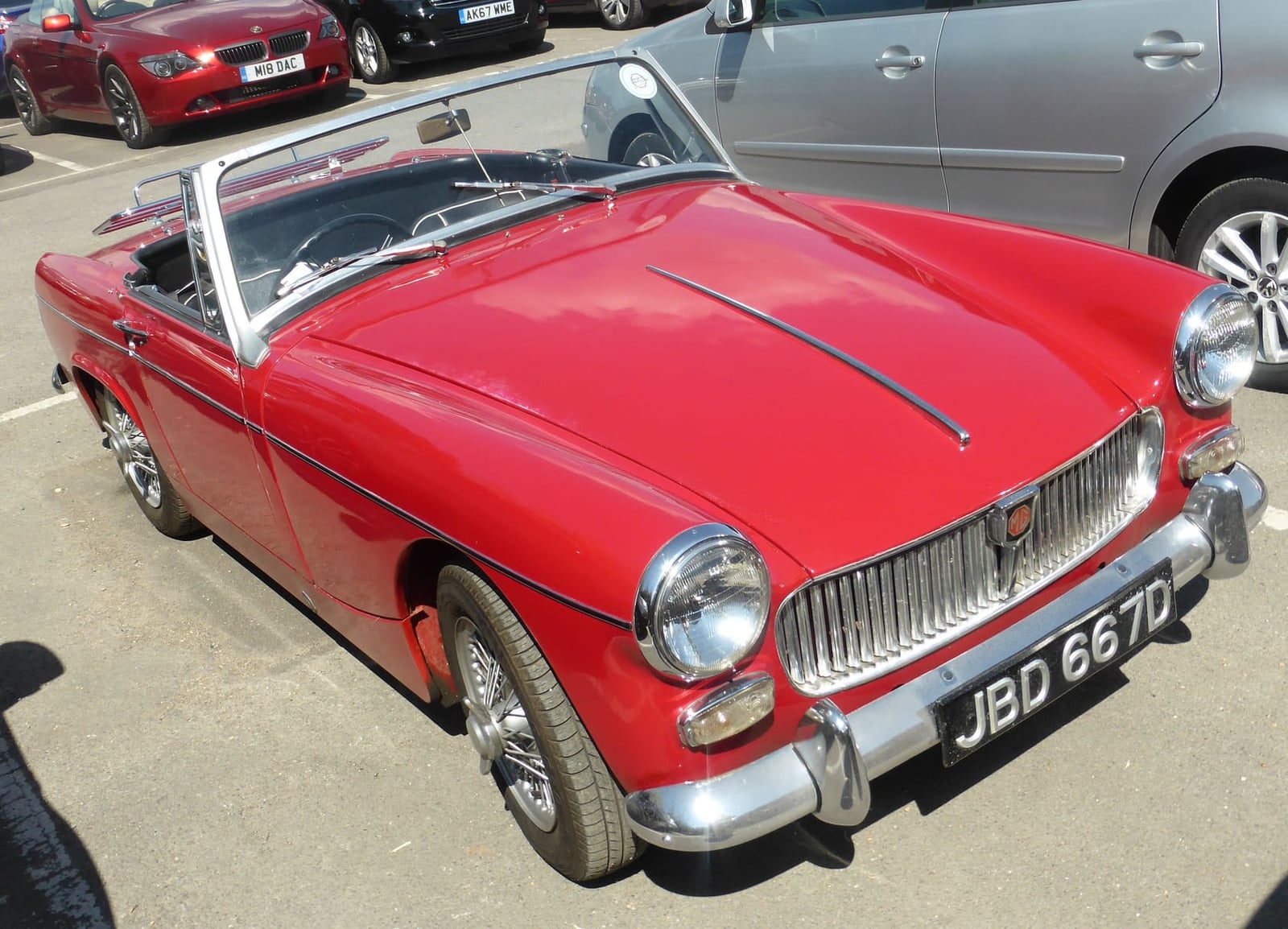 A red 1966 MG Midget Mk II with a UK registration parked at a show