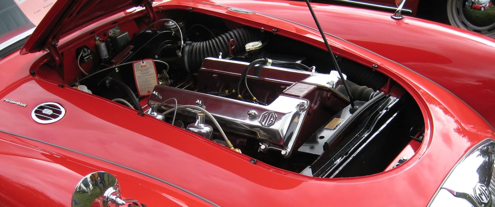 The engine bay of a red MGA Twin Cam, showing the twin-overhead-camshaft engine and its polished cam covers