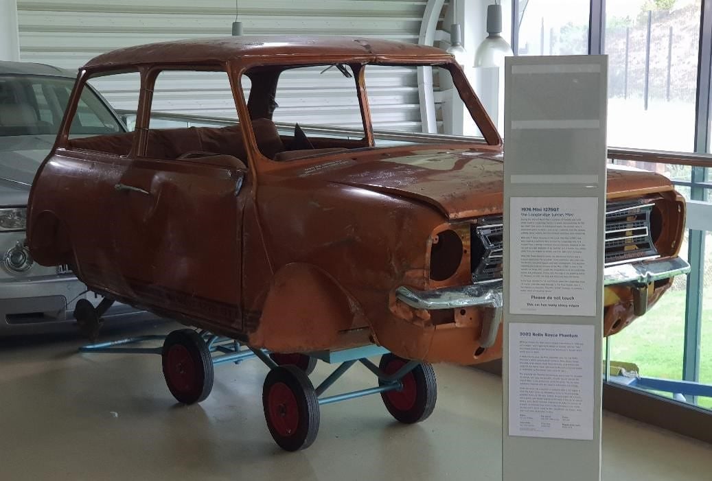 A Mini stripped to a bare shell under restoration, on a display stand