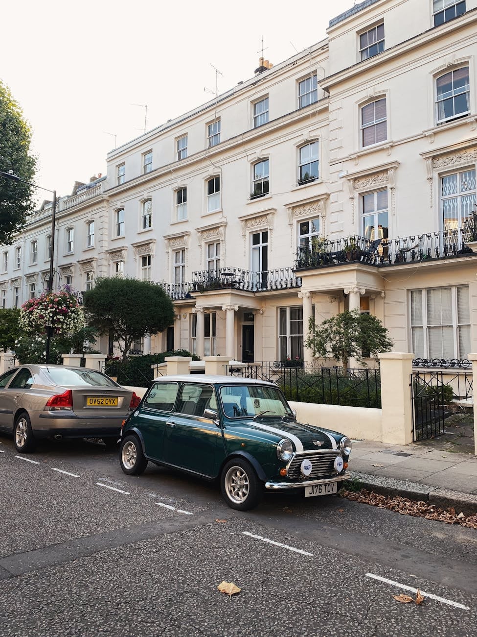 A green Mini Cooper with a white roof on a street, front view