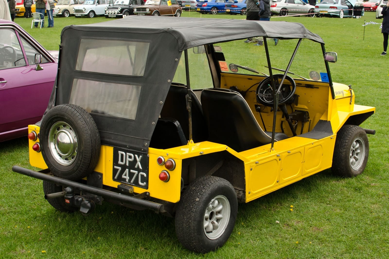 A yellow early British Mini Moke, side view