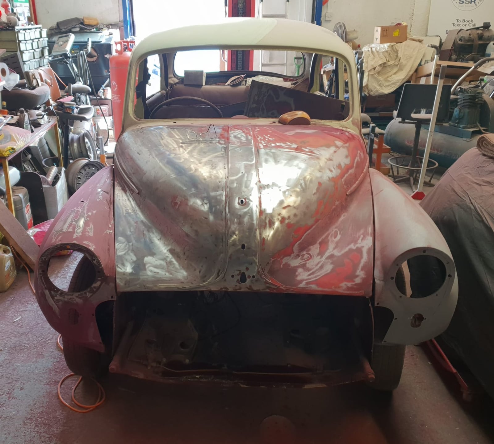A 1967 Morris Minor 1000 in bare metal and primer under restoration in a workshop