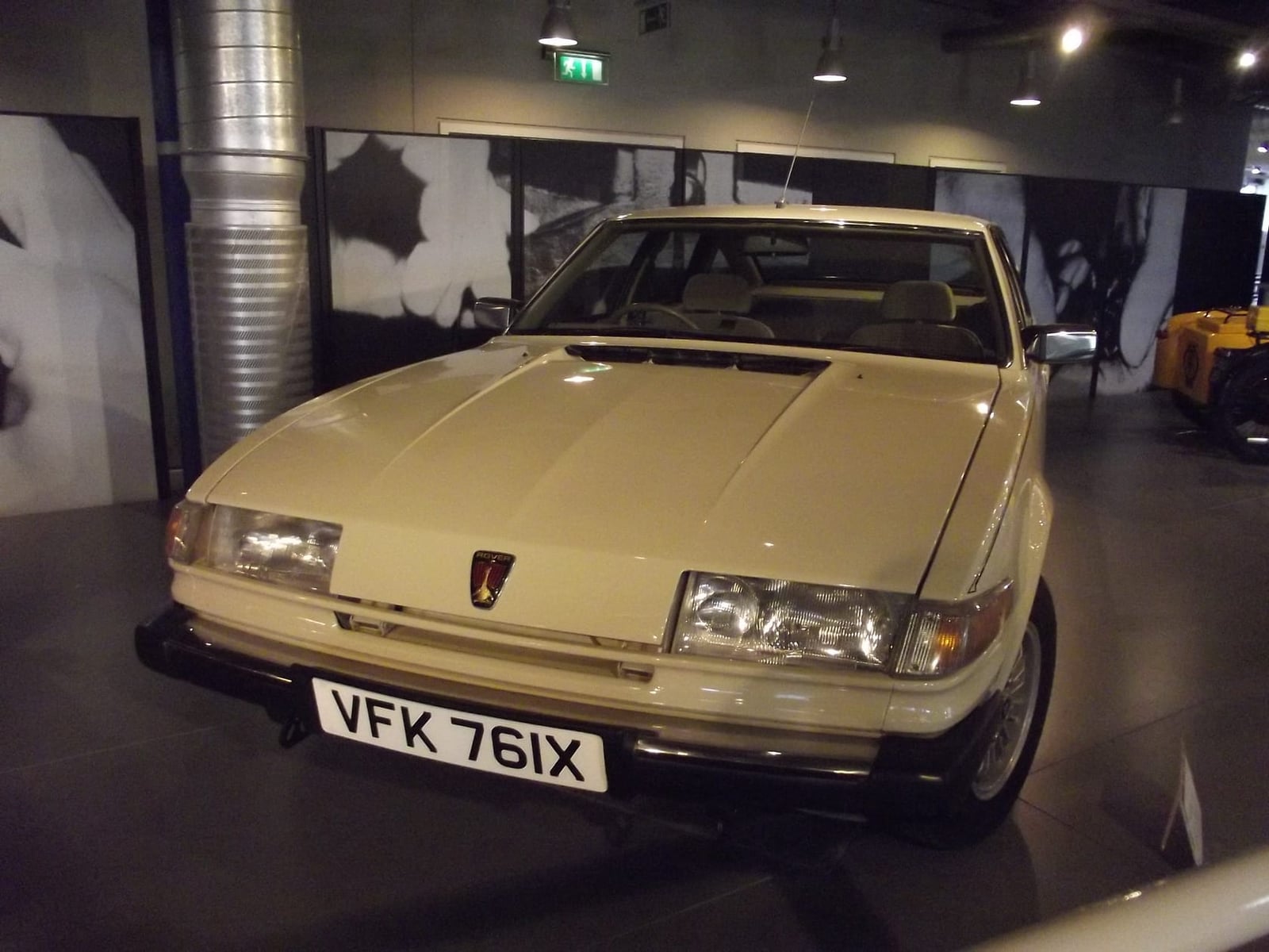 A gold Rover SD1 on display in a museum gallery, front three-quarter view, UK registration VFK 761X