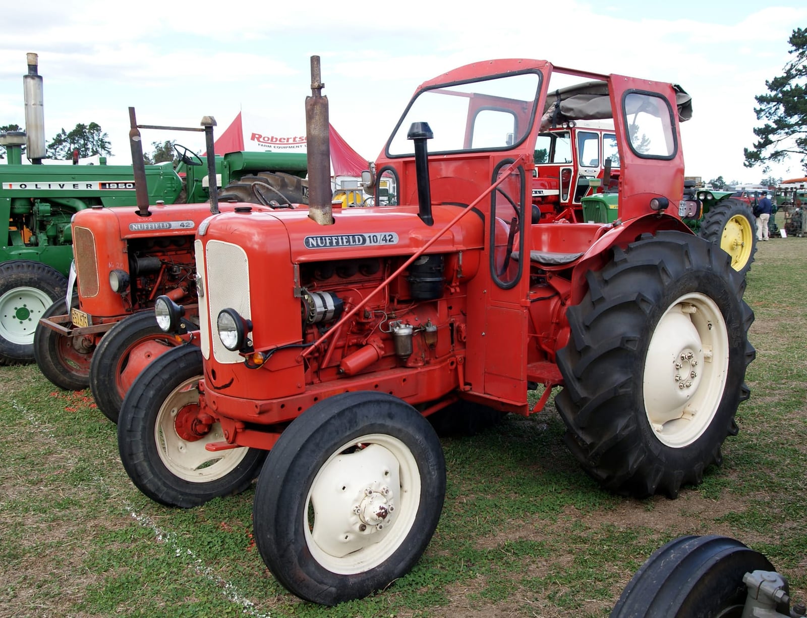 An orange Nuffield 10/42 fitted with a cab, at a show