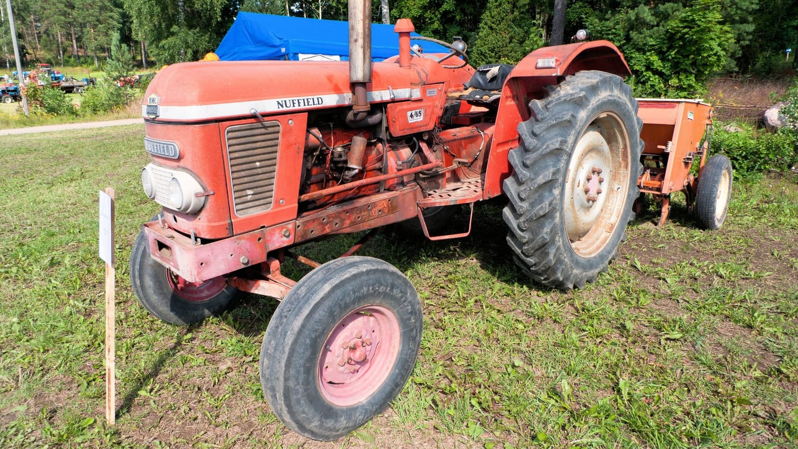 An orange Nuffield 465 with a seed drill attached, at a show