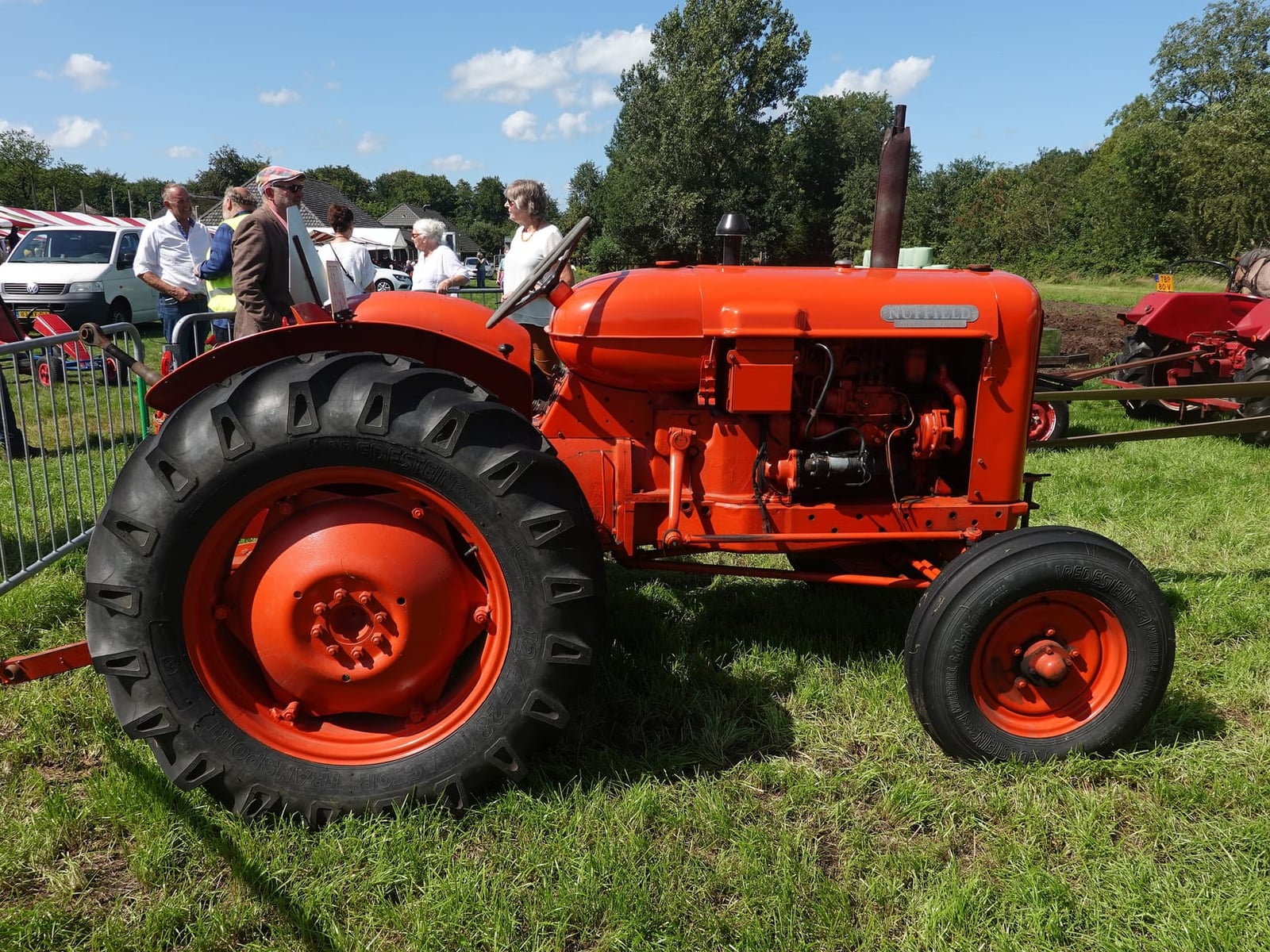 An orange Nuffield Universal in side profile at a show