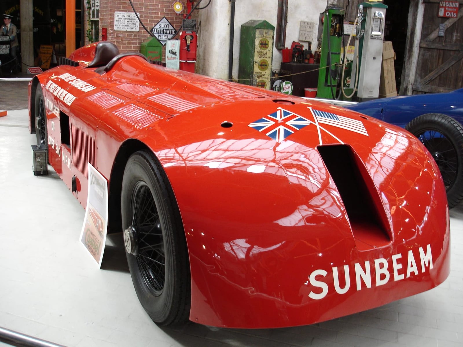 The red Sunbeam 1000hp land speed record car of 1927, a long low two-seater with exposed wire wheels, on display in a museum hall