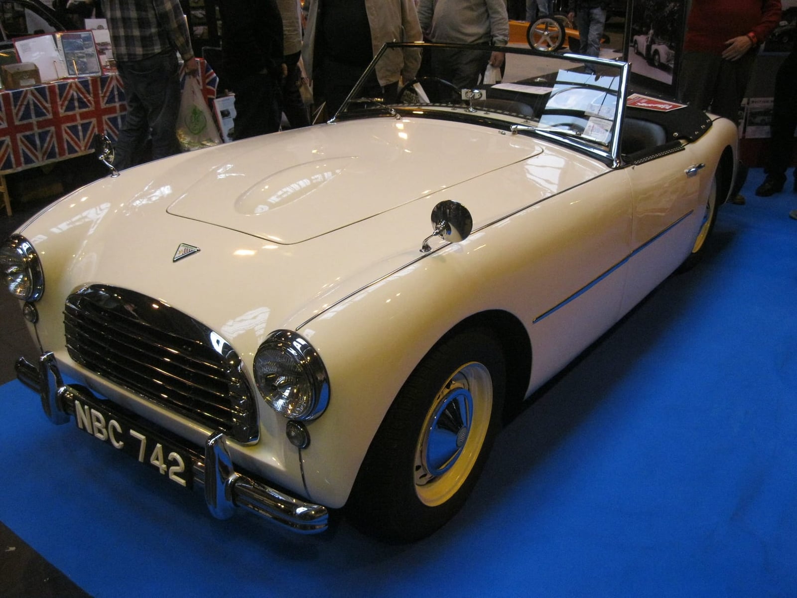 A cream Swallow Doretti sports car on indoor display, front three-quarter view, UK registration NBC 742