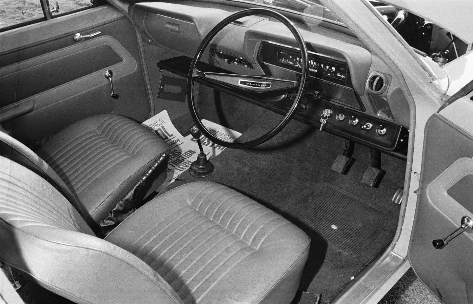 A black and white period press photograph of a Vauxhall Viva interior showing the dashboard, steering wheel and front seats