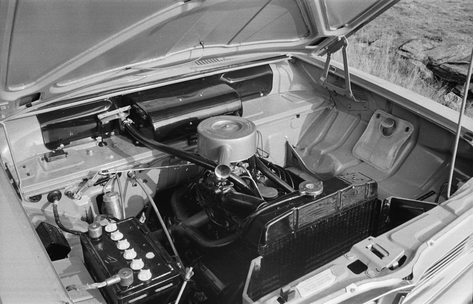 A black and white period press photograph of a Vauxhall Viva engine bay with the bonnet raised