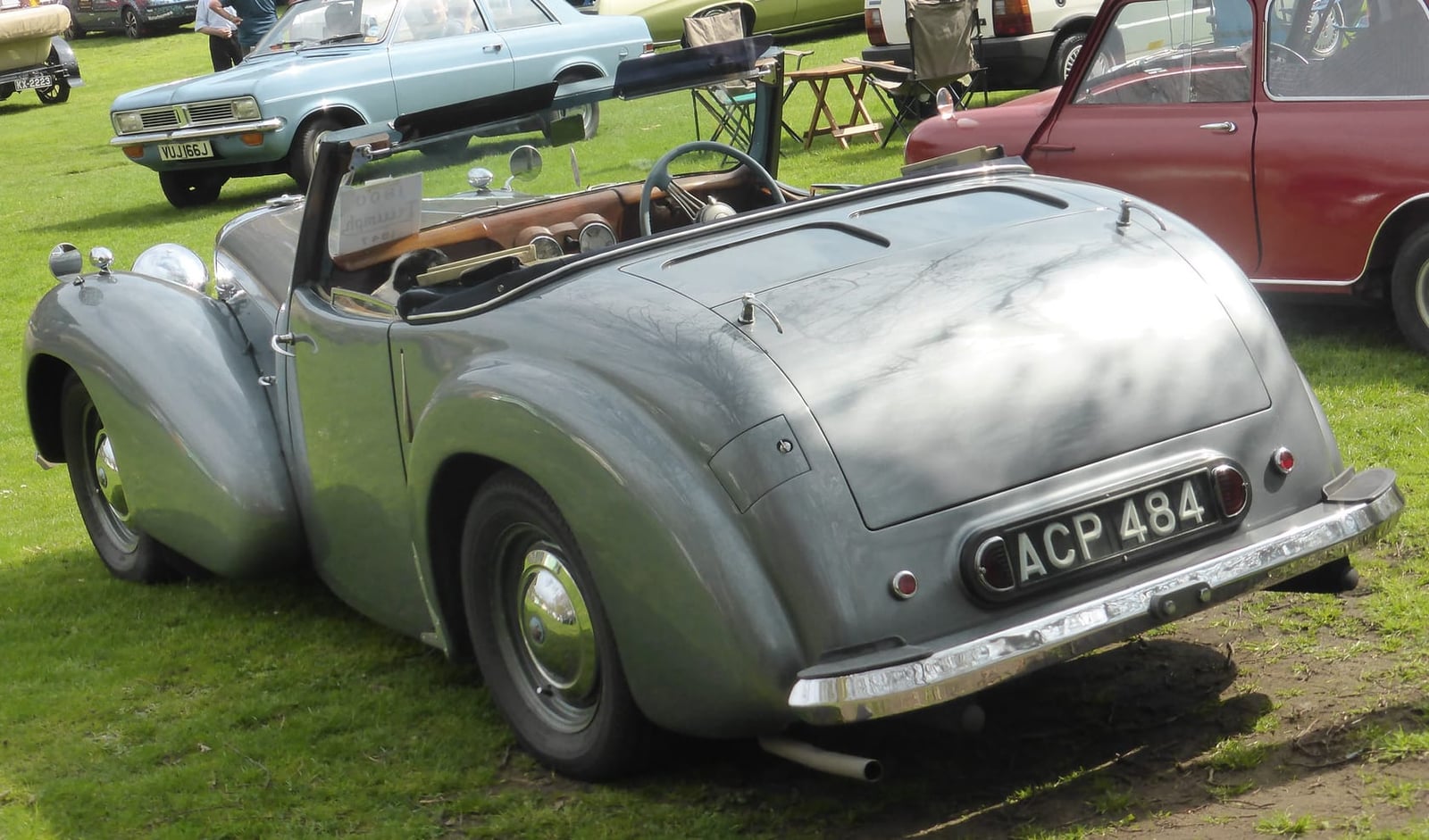 A grey Triumph 1800 Roadster on grass at a classic car show, rear three-quarter view