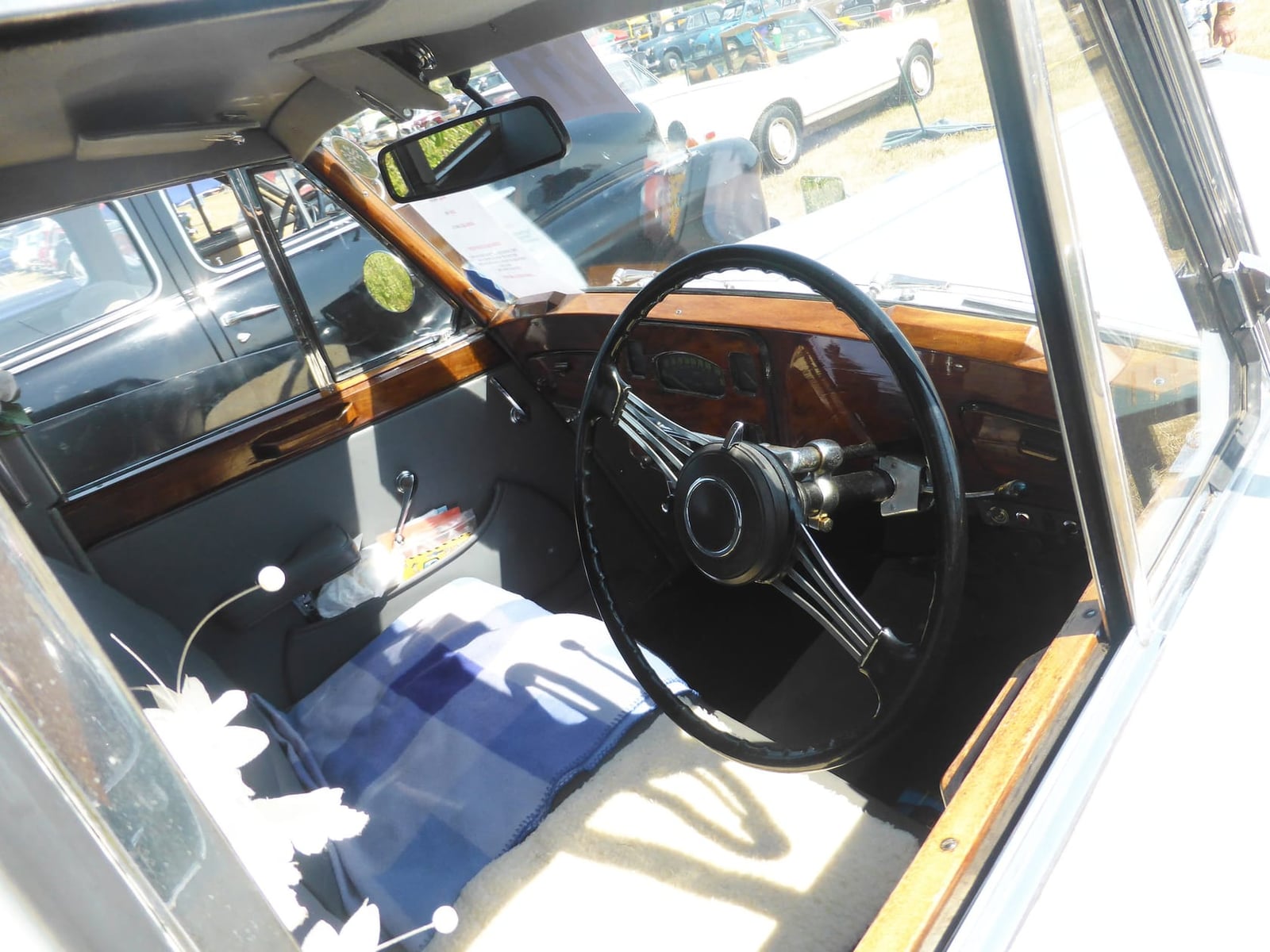 The interior of a 1950 Triumph Renown showing the wooden dashboard, large steering wheel and pale leather seats