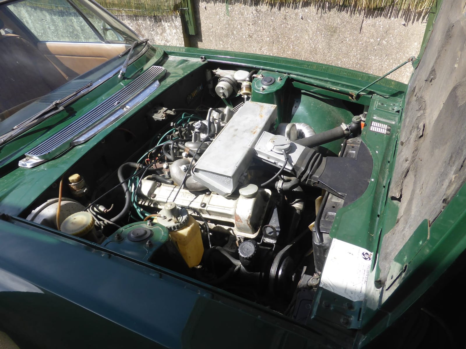 The engine bay of a green 1976 Triumph Stag with the original Triumph 3.0-litre V8 in place