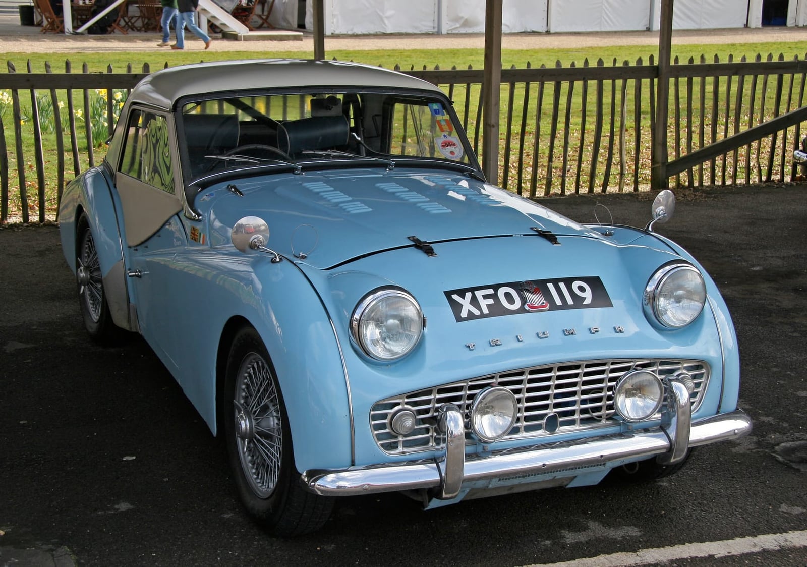 A pale blue Triumph TR3 with wire wheels, front three-quarter view at a show