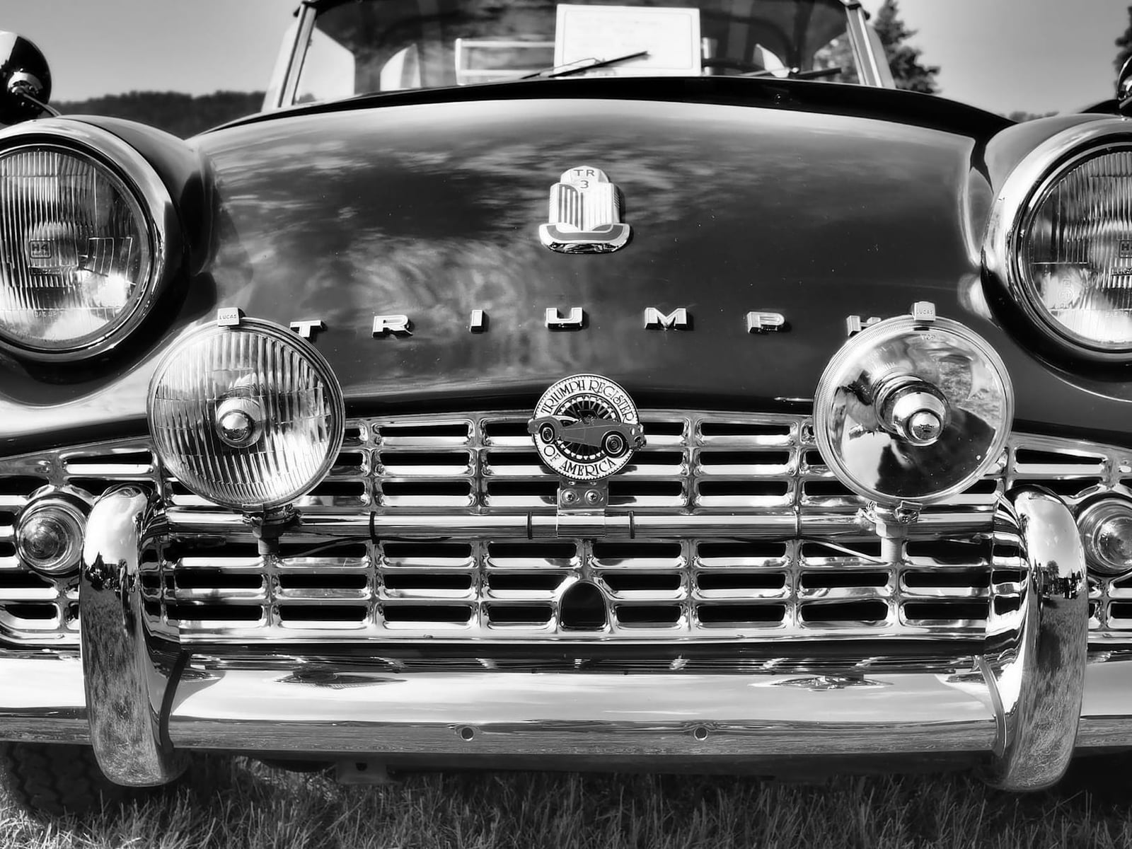 Black-and-white head-on view of an early Triumph TR3 showing the narrow recessed grille and Triumph lettering