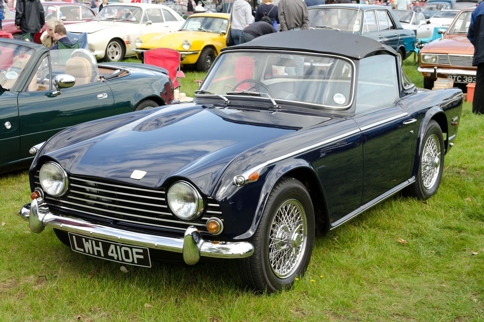 A green Triumph TR5 with the hood down at a show