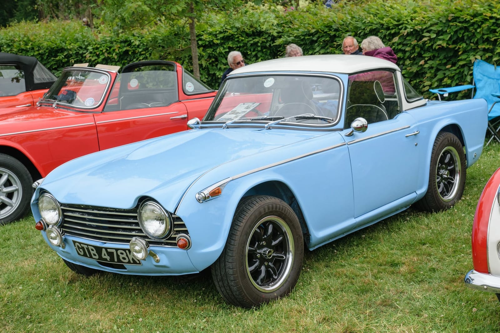 A pale blue Triumph TR5 with the hood down on grass